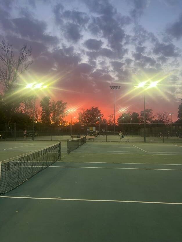 Floodlit outdoor tennis courts at sunset for evening rally practice and tennis lessons