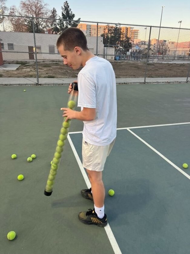 Junior competitive tennis player collecting balls during high-performance training in Los Angeles