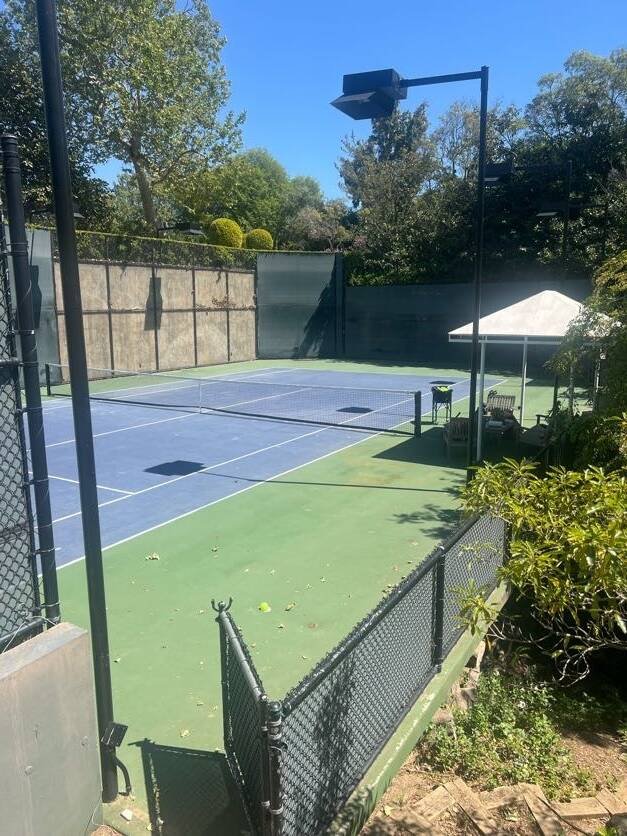 Blue and green outdoor tennis court with a shaded seating area for private tennis coaching serving Valley Village