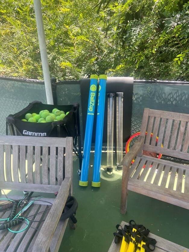 Tennis rackets, ball hopper and pickup tubes ready for beginner tennis lessons in Los Angeles
