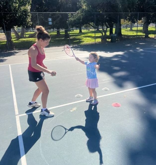 Coach helping a young beginner practice a tennis swing during a kids tennis lesson in Los Angeles